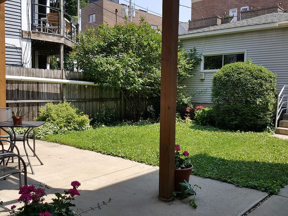 Backyard with garden. Cement patio with table and chairs.