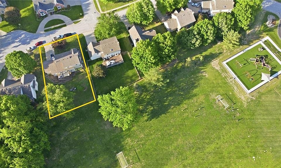 Expansive rear yard bordering a large green space featuring a play structure