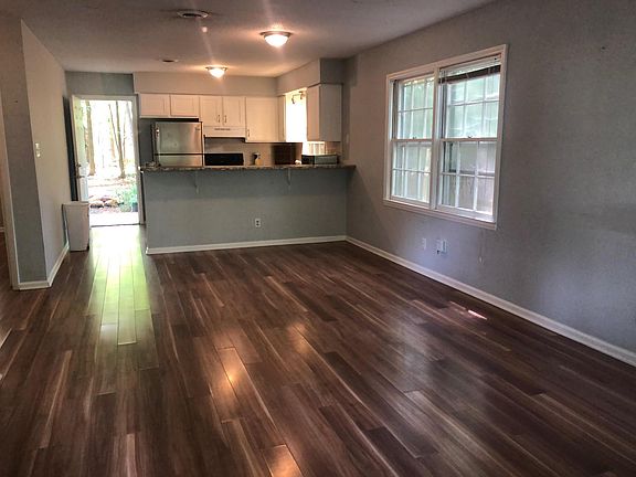Side B, Living Room and Kitchen - open concept with bar/counter. All Appliances included; Refrigerator, Stove, Dishwasher, Clothes Washer and Dryer. Door by refrigerator leads to back patio, partially fenced yard and Carrboro deer path in the woodsy bac