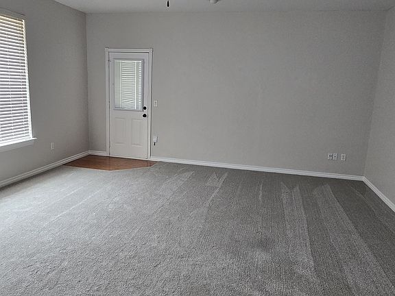 Large living room featuring new carpet, a ceiling fan, and direct access to the backyard through a private exterior door.