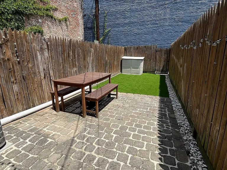 Backyard with stone patio, outdoor furniture, storage shed, and turf area