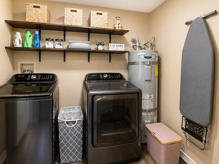 Dedicated laundry area with full-size washer and dryer, wall shelving for supplies, and space for sorting and folding.