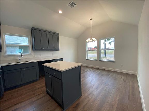 Kitchen with a chandelier, lofted ceiling, dark wood-style flooring, hanging light fixtures, and a center island