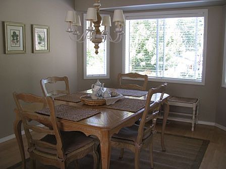 Dining room with maple hardwoods and bay window with wood blinds