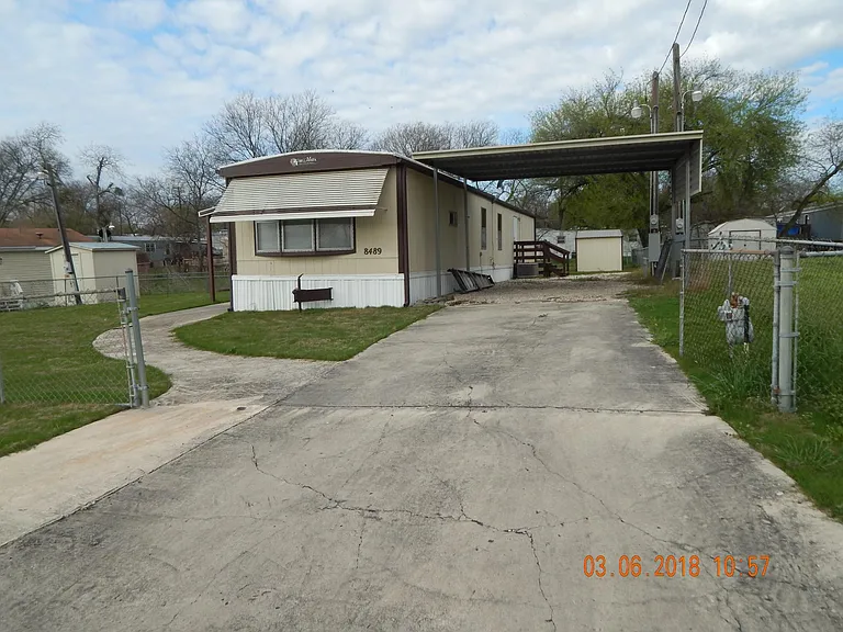 Front of home showing large driveway and carport.