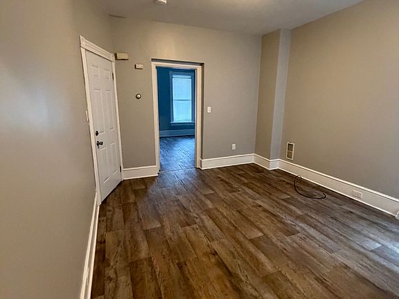 Living room with front door on the right. New flooring and paint.