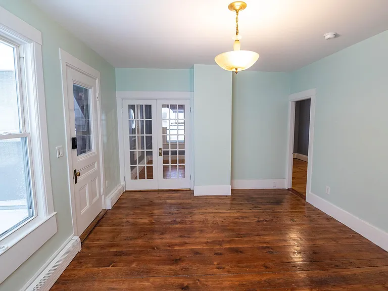 super sunny living room with vintage lighting restored pine floor and showing french doors to bedroom #1 and door to bedroom #2