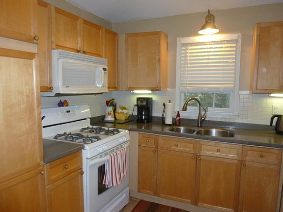 The large eat in kitchen runs the width of the back of the home. Stained maple cabinetry, gas stove with builtin microwave, undermount sink with Corian counters and featuring vaulted ceilings, mudroom/laundry room/office adjacent to eatin area with separate entrance.