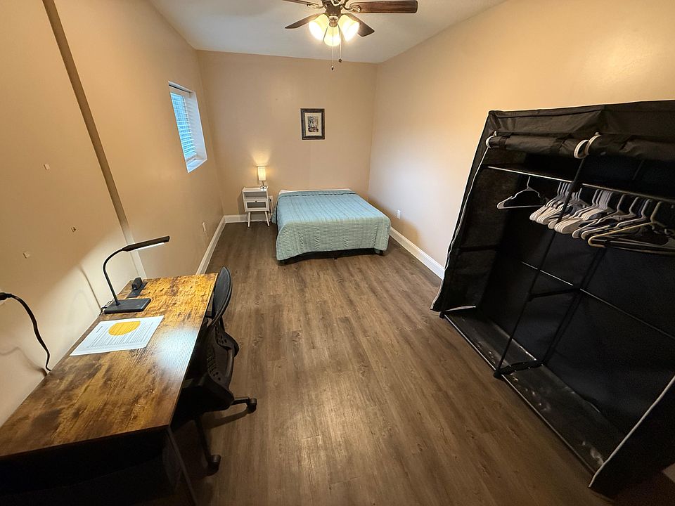 Full size bed with end table and light as well as a desk, office chair and lamp