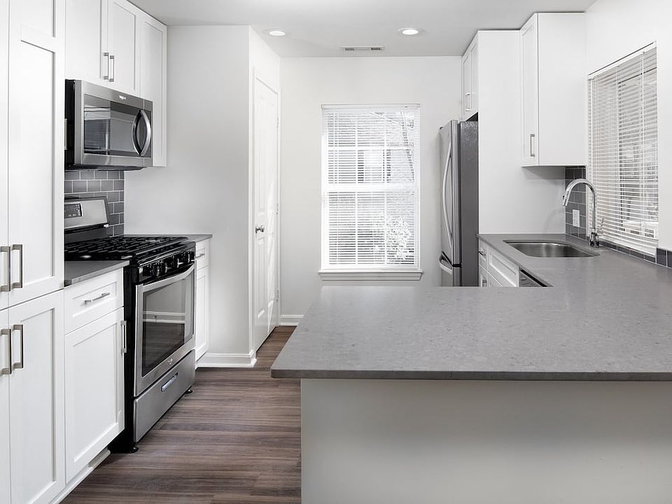 Kitchen with gray quartz countertops, tile backsplash, stainless steel appliances, and upgraded fixtures