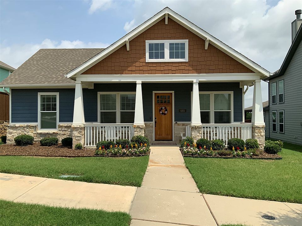 Craftsman-style facade with a prominent front porch, stone accents, and varied siding materials