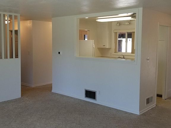 In living room looking into kitchen and dining room to right, hallway to bedrooms to left