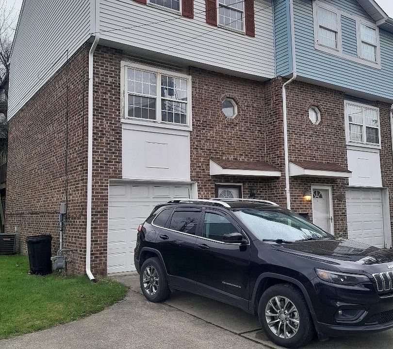 Front of the townhome with garage and parking pad as well as side yard