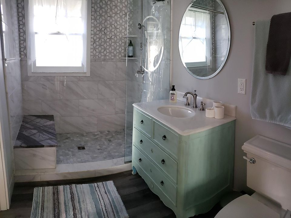 The charming bathroom boasts dual shower heads with handset and rain shower, marble mosaic tiles and vanity top, and comfort height toilet.