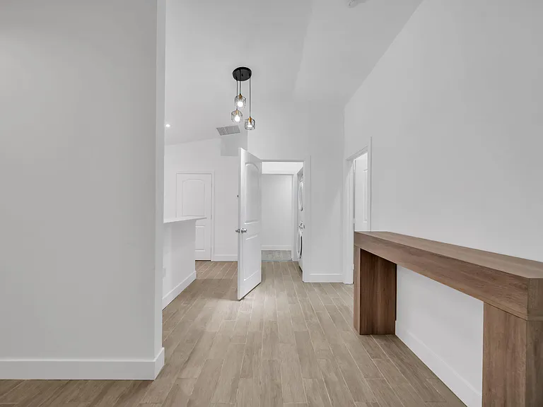 Wide hallway/utility area with durable tile flooring, high ceilings, and a built-in desk nook plus nearby laundry access.