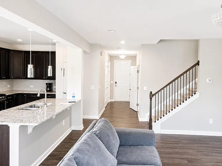 Open-concept kitchen with granite island and pendant lighting, flowing into the main living area near the entry and stairs.