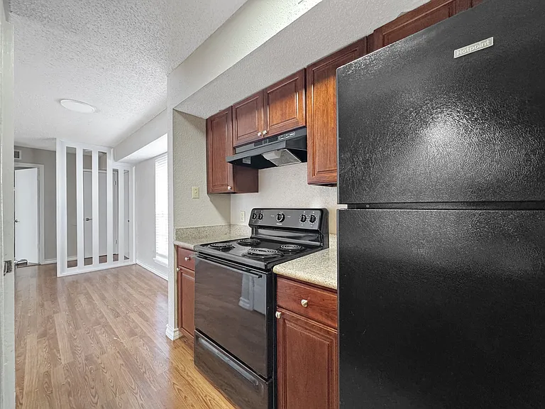 Updated kitchen with rich dark wood cabinetry and modern black appliances at Borders Apartments in Brownsville TX.