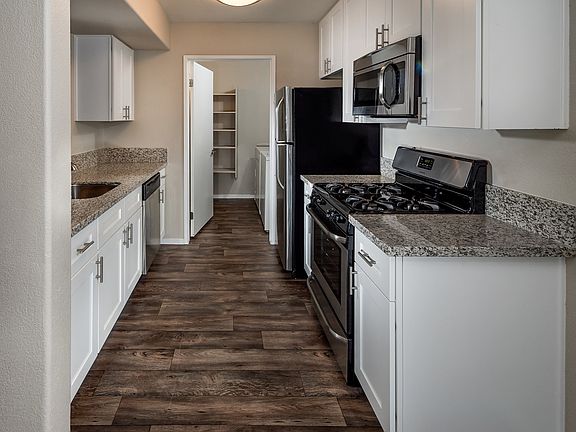 Spring Valley Apartments - Aviara - Kitchen with spacious countertops, white cabinets, and stainless-steel appliances
