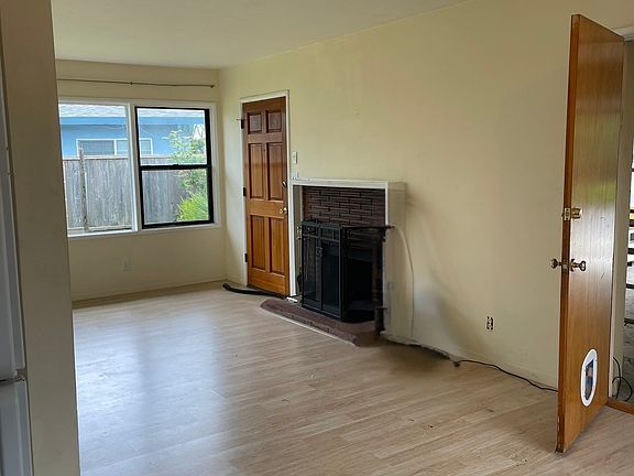 Sunny Living Room With Fireplace, Taken From Dining Room, showing Door Leading to Garage