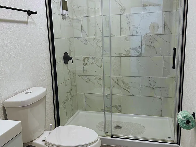 Shower space with immaculate toilet and toilet paper.