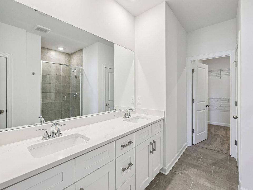 The primary bathroom boasts a dual-sink vanity and modern walk-in shower.