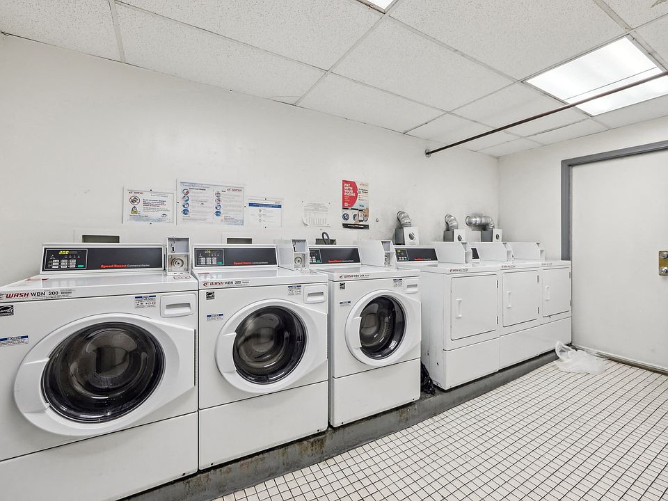 Laundry room with commercial washers and dryers, tiled floor, and posted instructions