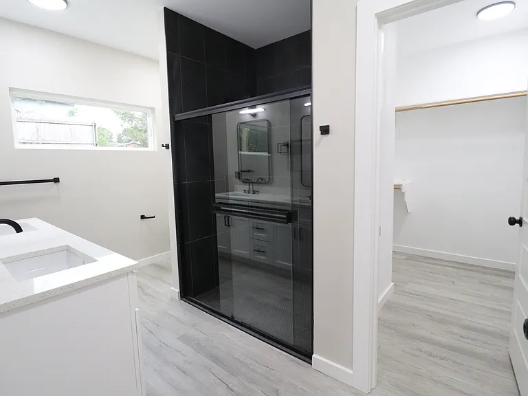 Beautiful primary suite bathroom with a stylish walk-in shower, modern black accents, and a generously sized walk-in closet.