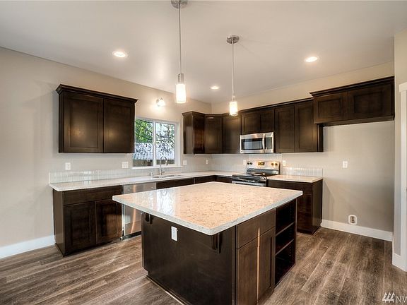 Spacious kitchen has lots of nice features, shelves & cabinets on island, walk-in pantry, stainless steel appliances, pendant lighting & quartz countertops. 