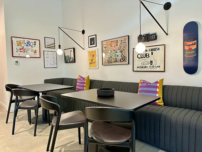Relax in the artistic common area with tables, chairs, and artwork on the walls at Alt Capitol Hill.