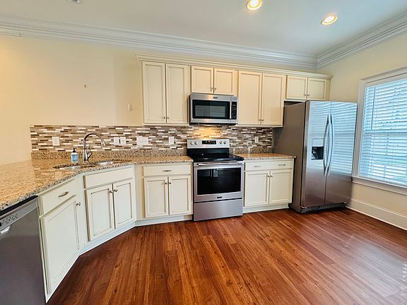 An open kitchen with granite countertop and stainless steel appliances.