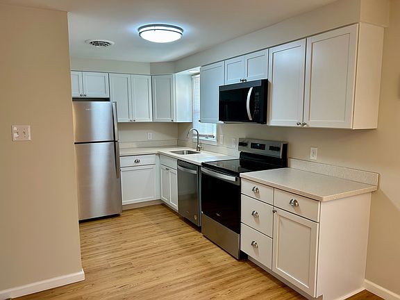 Brand new kitchen with stainless steel appliances, including a dishwasher and over the range microwave.