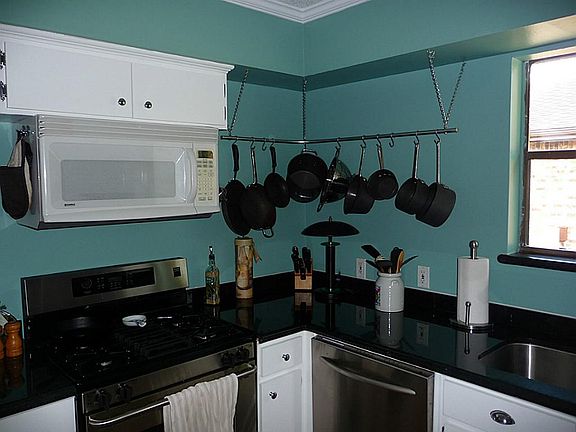 Kitchen with gas stove and microwave, pot rack