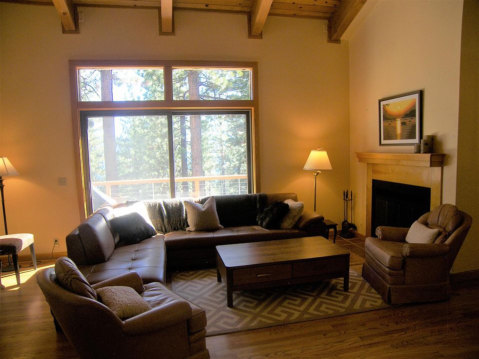 Cozy living room with wood burning fireplace. Pretty, serene wooded view with peak of lake.