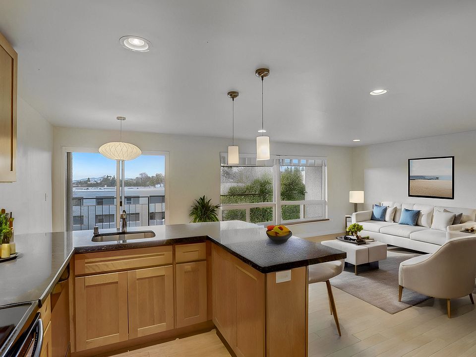 A modern, open-concept kitchen and living area featuring stylish furnishings, ample natural light, and a welcoming atmosphere perfect for relaxing or entertaining.