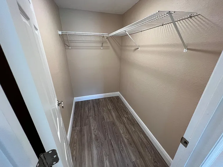 Spacious walk-in closet with durable flooring and wire shelving for organized hanging and storage.