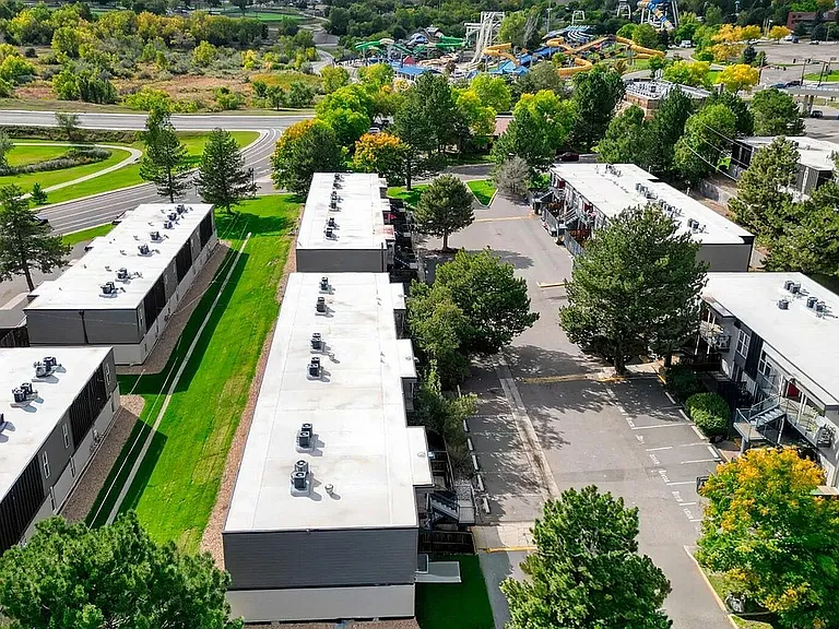 Aerial view of modern apartment complex surrounded by lush greenery and scenic pathways, ideal for tranquil living.