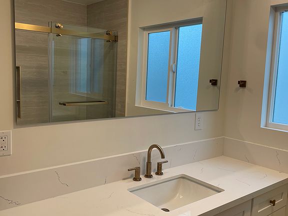 Bathroom 1 - custom-designed vanities, Delta gold hardware, large-format tile, and modern rainfall showers