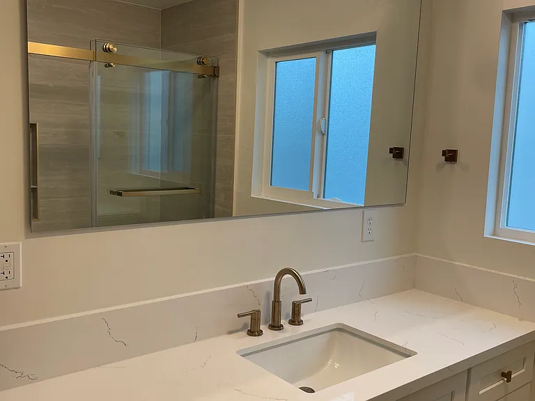 Bathroom 1 - custom-designed vanities, Delta gold hardware, large-format tile, and modern rainfall showers