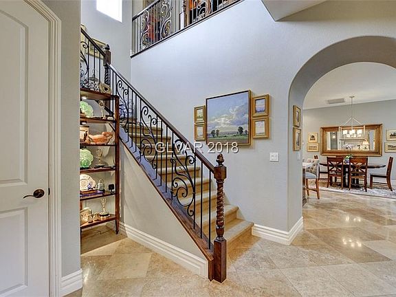 Enter into Foyer with travertine flooring, two-tone paint .... overlooking wrought iron staircase and view into Kitchen/Dining/F