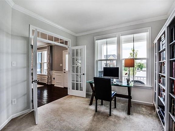 Glass French doors open to the first floor den with an impressive wall of bookshelves.