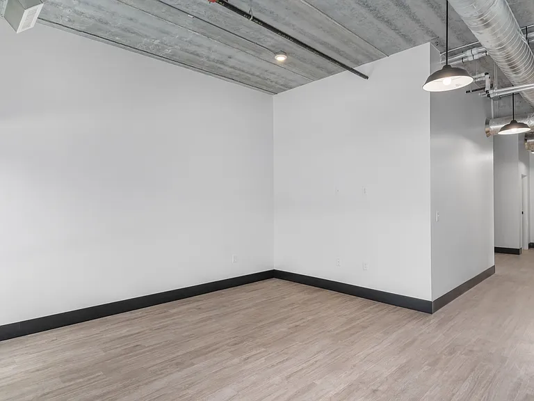 Modern industrial loft space with exposed ductwork and sleek lighting, featuring light hardwood flooring and white walls for a spacious, airy feel. Modern industrial loft space with exposed ductwork and sleek lighting, featuring light hardwood flooring an