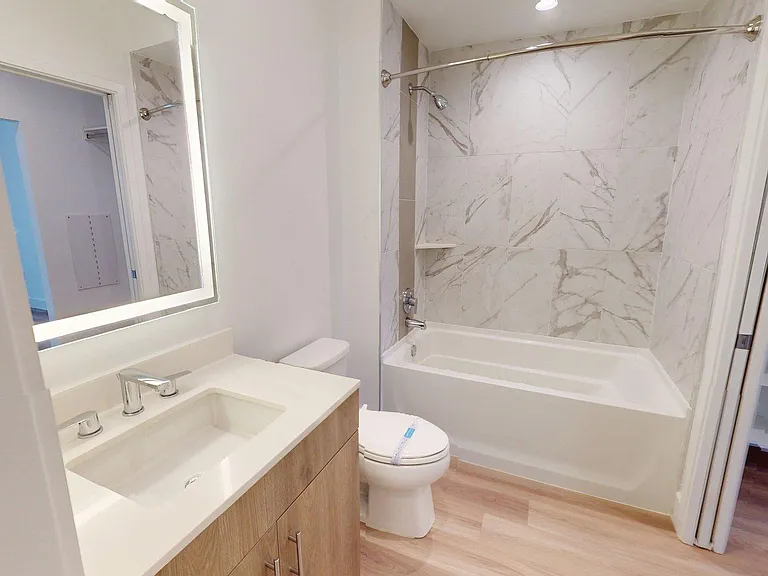 Apartment Bathroom with large soaking tub, Single Sink, LED vanity mirror and light wood panel flooring