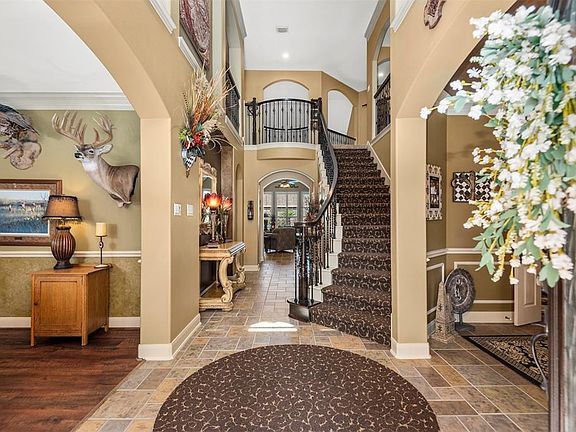 Amazing 2 story foyer with tile flooring, multiple art niches and a curved staircase with wrought iron spindles.