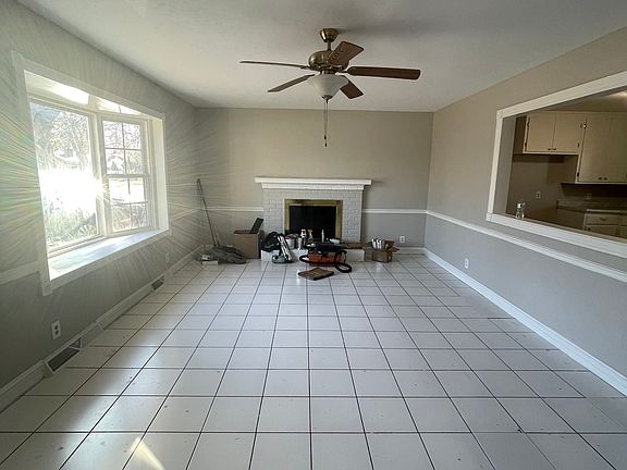 Living room with ceiling fan and fireplace, tile floors for easy cleaning.
Freshly painted and bay window.