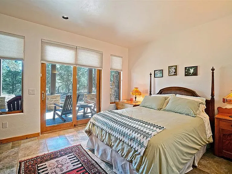 Third bedroom downstairs with queen bed and view to patio