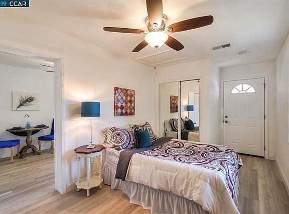Bedroom with mirrored sliding door closet and ceiling fan.