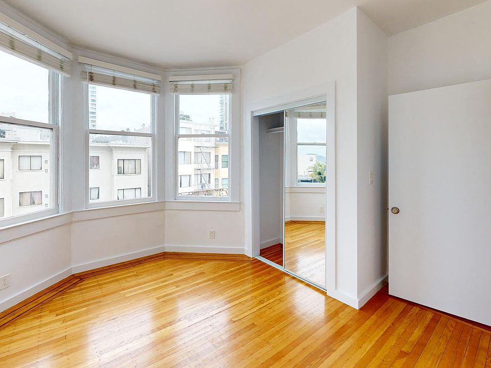 Bright bedroom with wood-like floor and a closet with mirror