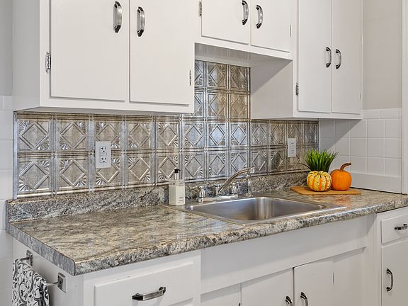 Updated kitchen with modern backsplash and stainless steel sink.