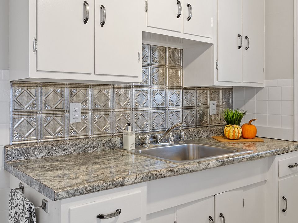 Updated kitchen with modern backsplash and stainless steel sink.