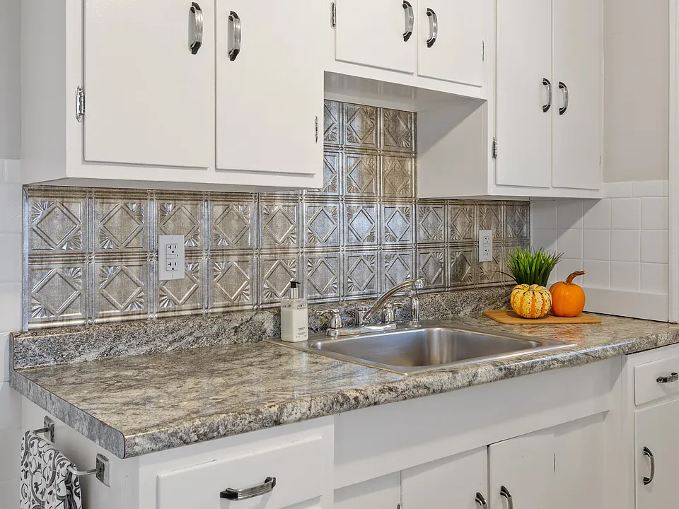 Updated kitchen with modern backsplash and stainless steel sink.